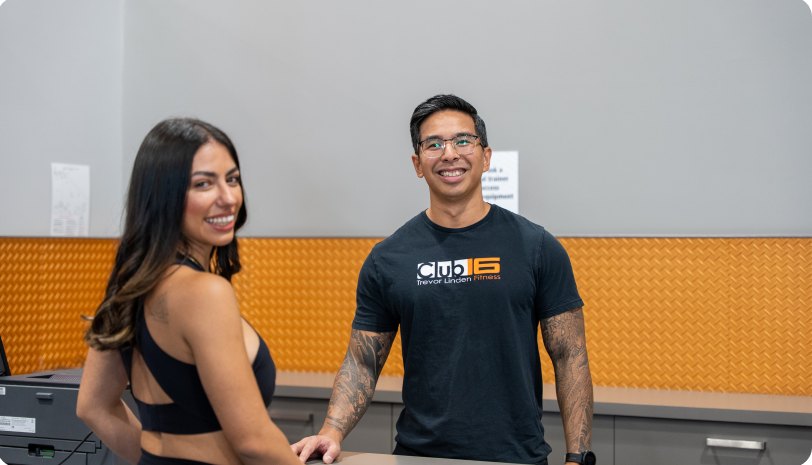 A personal trainer with a client at the front desk